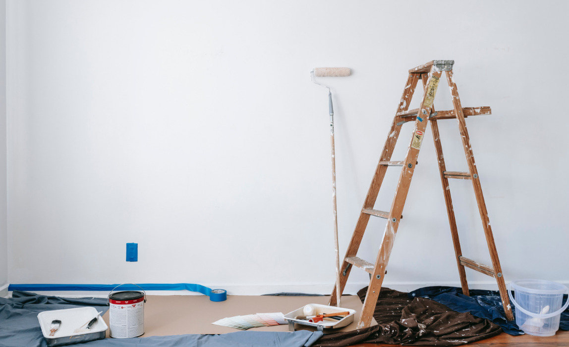 escabeau en bois avec rouleau de peinture et pot de peinture dans une pièce en travaux